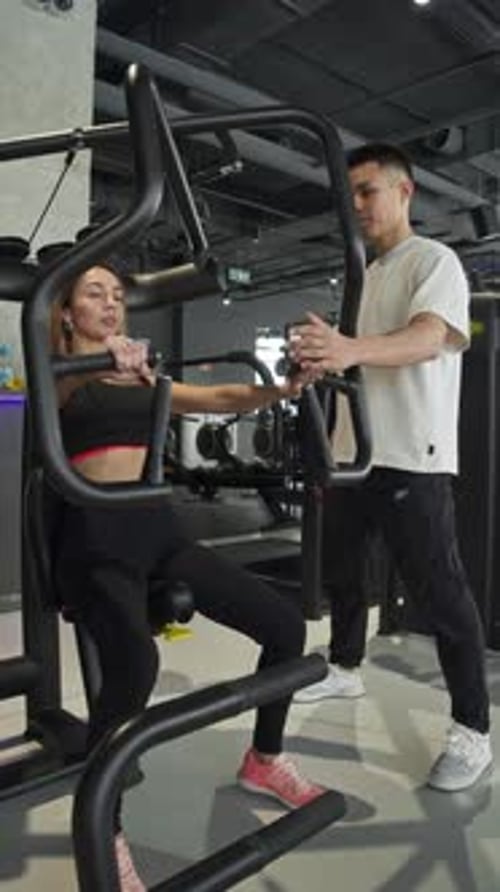 Woman is Engaged in Workout Session at Gym Accompanied By Personal Trainer She is Performing Chest