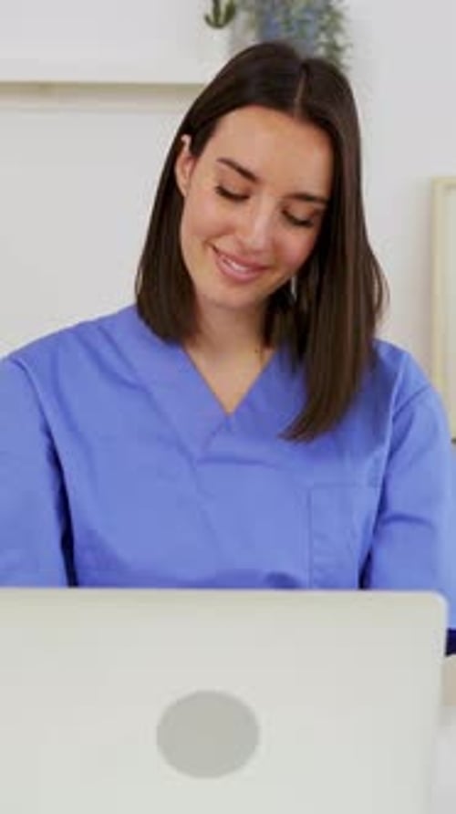 Smiling Nurse Working with Laptop and Medical Records at Doctor's Office