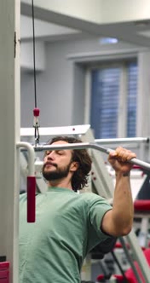 Vertical Video of a Caucasian Man Working Out in the Gym Workout for Back Muscles