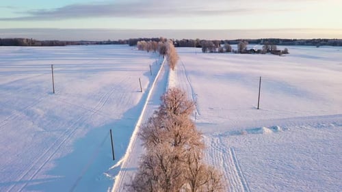 Empty rural road covered in white snow, aerial fly backward shot