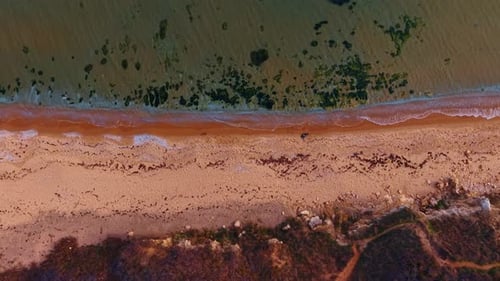 Empty sandy beach and rocky shore of the sea. Clear seawater slowly splashes on the coast.