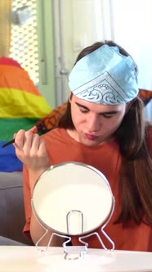 Young Adult Applying Makeup with Rainbow Flag Background
