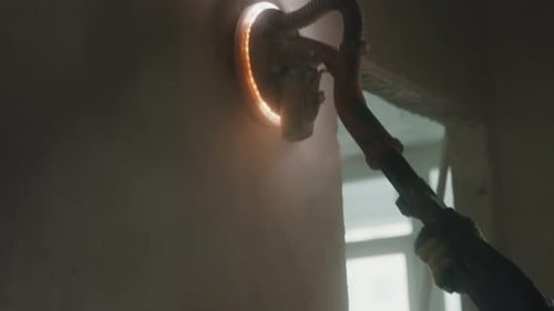 Worker Sanding Interior Wall with Electric Drywall Sander Close Up