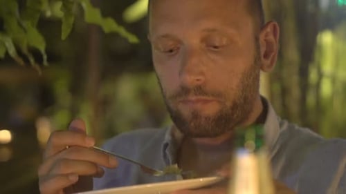 Man Eating Meal Sitting In Cafe At Night