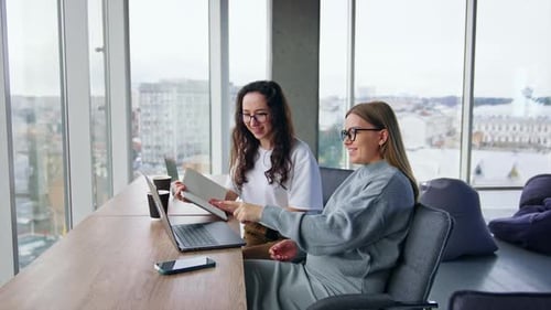 Two Young Women Discussing Business in a Modern Office