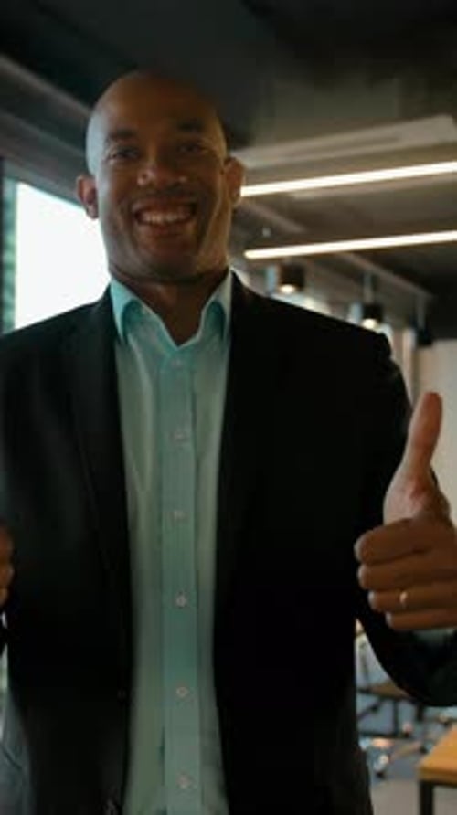 Smiling Man Gives Thumbs Up in Office Setting