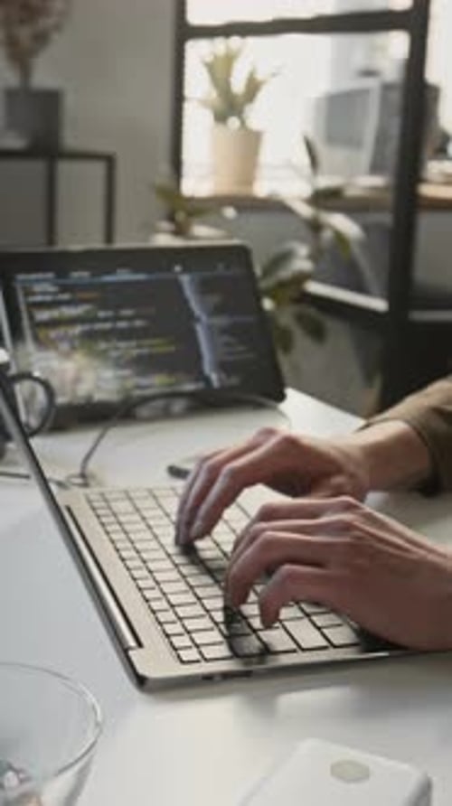 Vertical of Unknown Male Programmer Typing Code on Laptop Keyboard in Office