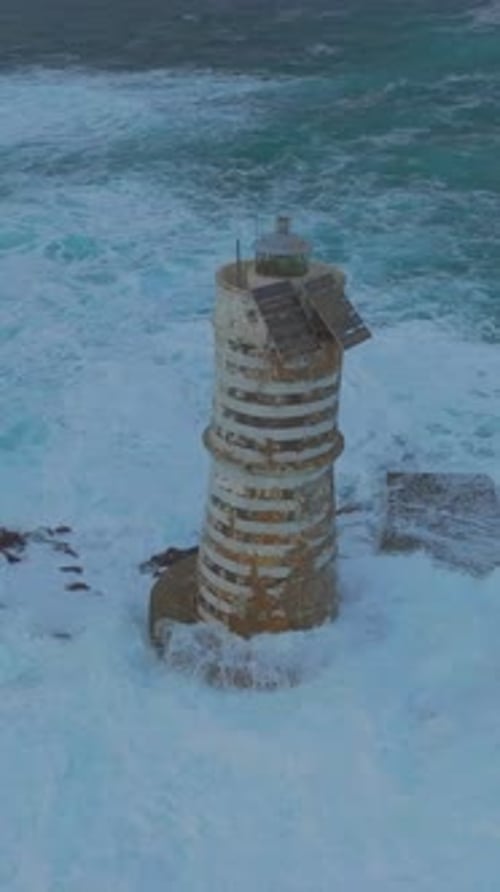 Aerial drone view of Mangiabarche lighthouse surrounded by waves