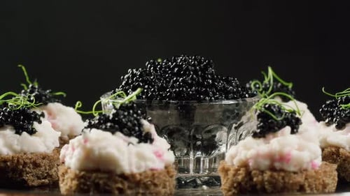 Black caviar sandwiches close-up. Beluga sturgeon salted roe in glass bowl. Raw seafood.