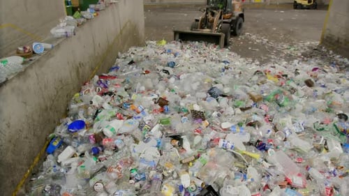 Excavator or Loader pushing a Pile Of Plastic Waste In Recycling Factory. Wide Shot