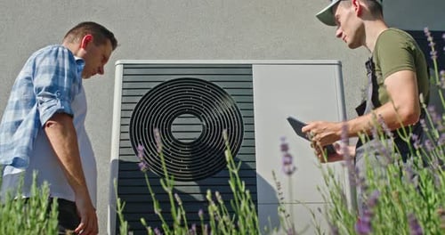 Technician and Homeowner Reviewing Heat Pump Setup in Garden