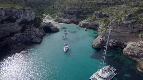 Drone View Moving Away From a Calm Bay with Few Boats on the Mediterranean Sea
