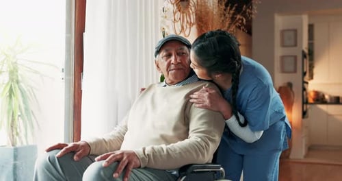 Caring Nurse Comforting Senior Man in Wheelchair