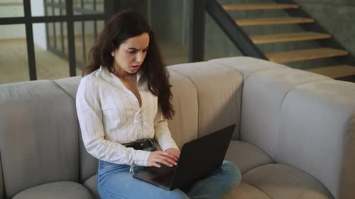Woman Works on Laptop with Concerned Expression Indoors