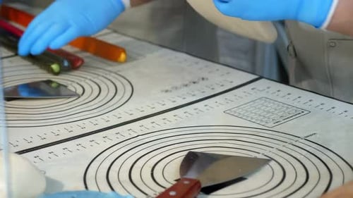 A Pastry Chef Rolling Out Soft Caramel in Gloves on a Table in a Pastry Shop