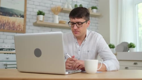 Man Working on Laptop with Coffee at Home