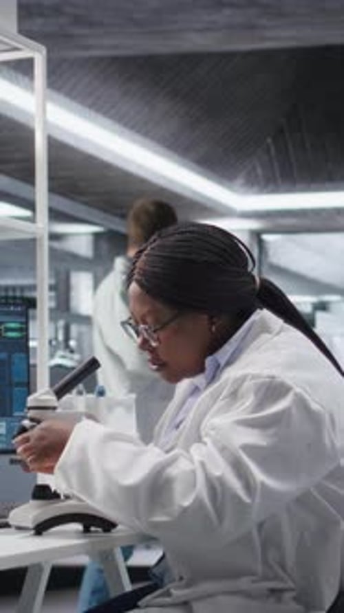 Vertical Video Black Scientist Examining Samples Under Microscope in a Modern Laboratory