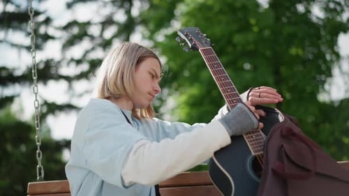 Teen Placing Acoustic Guitar into Gig Bag in Park