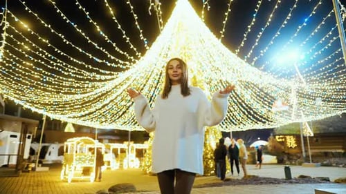 Woman Posing near Christmas Lights at Night