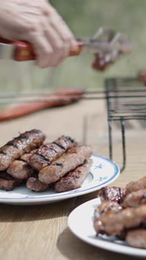 A Man Removes Meat From Grills with Tongs