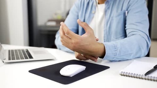 Close up. African american businessman holding wrist in pain while using computer mouse sitting