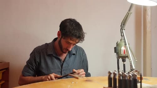 Man Filing Metal at Jewelry Making Desk