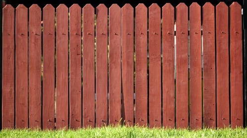 Red Wooden Picket Fence Creating a Boundary with Green Grass Below Privacy Concept