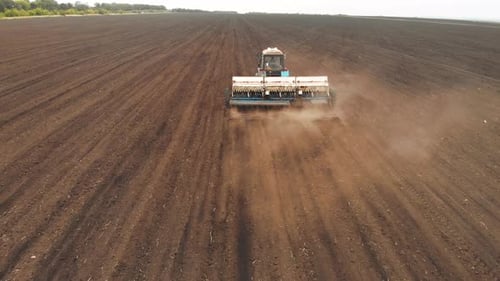 Drone Sliding Shot of a Farmer in Tractor Seeding on Sunny Day Footage of Sowing Agricultural Crops