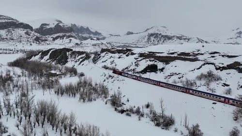 Lokomotive und Personenzug bewegen sich in verschneiten Bergen