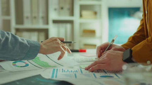 Two experienced creatives at an advertising company focus on analyzing graph data and comparing it