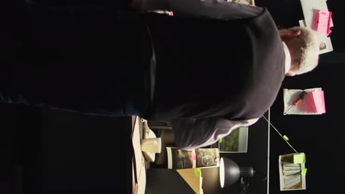 Detective Examining Evidence in Dark Room