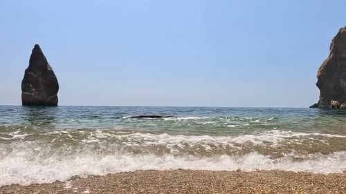 Pequeñas olas marinas borrosas, suaves olas espumosas que bañan la playa de arena dorada y las costas rocosas volcánicas Nadie