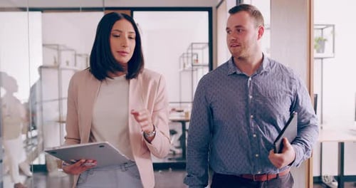 4k-Videomaterial von zwei jungen Geschäftskollegen, die sich unterhalten, während sie durch das Büro gehen