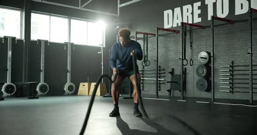 Man, battle rope and workout in gym, cardio exercise and muscle building for fitness