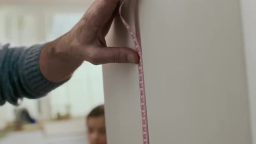 Grandparent Measuring Child's Height on Wall with Tape