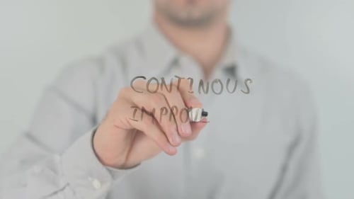 Hand Writes Continuous Improvement on Clear Surface