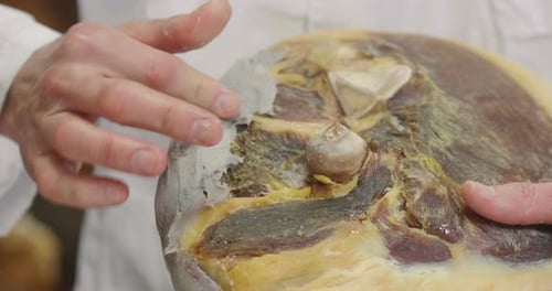 Close-up of a hand that gathers the ham with fat before it is seasoned, to give flavor and protect