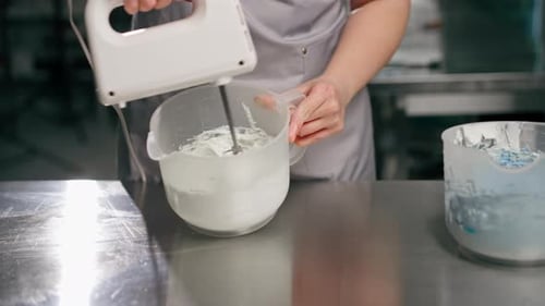 Closeup of Female Baker in a Professional Kitchen Mixing Cream with a Mixer