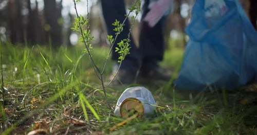 Un hombre recoge basura de una pila que yace en el bosque y la coloca en una bolsa de plástico