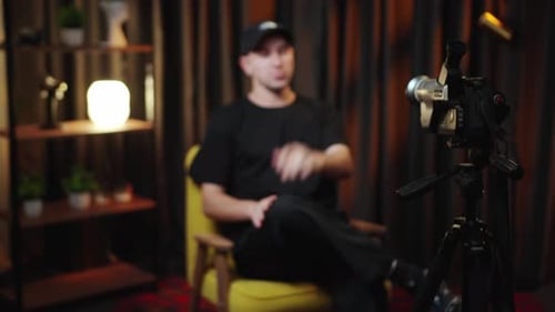 Man Sitting in Chair Recording Video with Camera