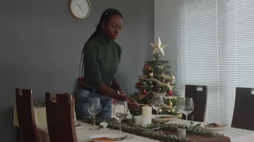 Woman Lights Candles at Christmas Table Setting