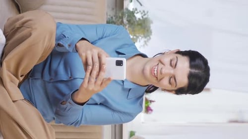 Vertical video of Woman laughing at phone message.
