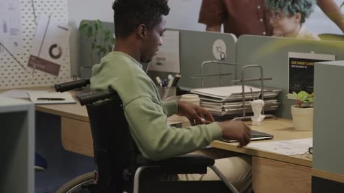 Homme noir en fauteuil roulant analysant un graphique commercial dans un espace de travail