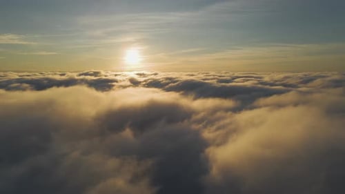 Aerial View of Vibrant Yellow Sunrise Over White Dense Clouds with Blue Sky Overhead
