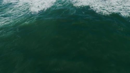 Aerial view of green ocean waves with white foam patterns