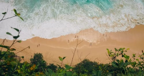 Top down view of ocean waves with white foam crashing at tropical sandy Kelingking beach. Powerful s