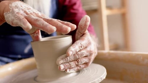 Mains de potier à longue barbe travaillant sur un vase en argile dans un atelier de poterie, Ralenti