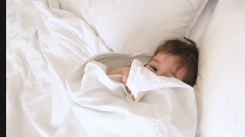 Child Resting Peacefully in Bed Under Blanket