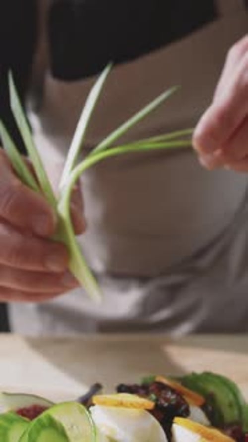 Close-up of Unrecognizable Chef Adding Decorative Leek Leaf to Dish
