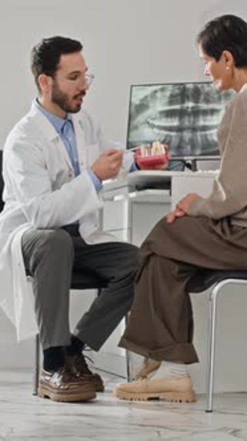 Dentist explaining teeth structure to woman in office